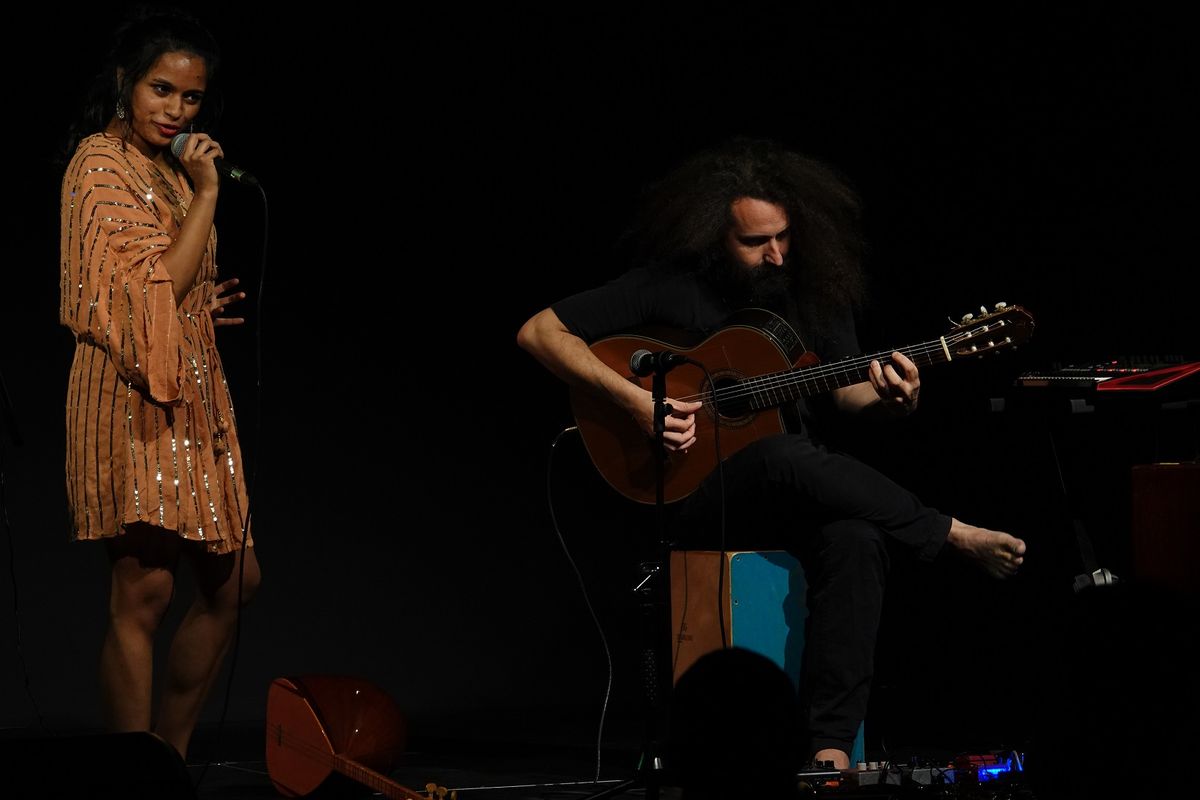 Singer and guitarist performing together against a dark background