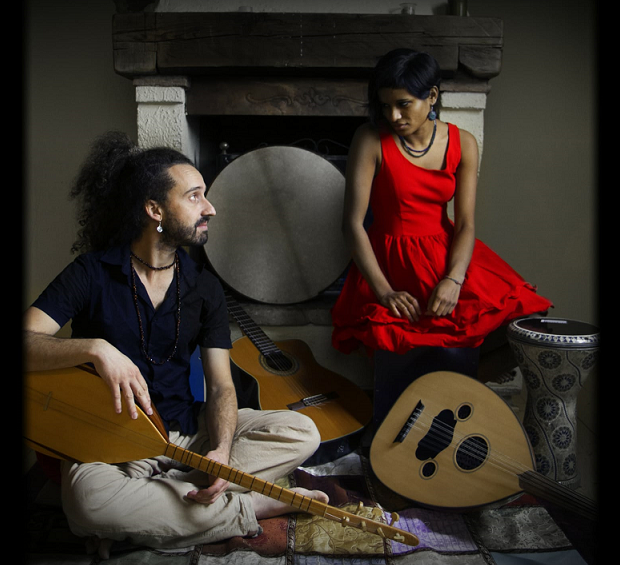 Two Mi Linda Dama musicians seated with string instruments