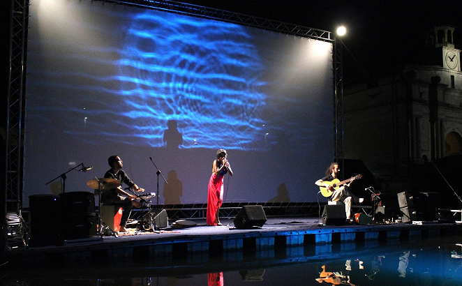 Mi Linda Dama performing in front of a blue projection